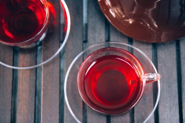 Bir bardak sıcak kırmızı amber çayı ve terastaki ahşap tepside eski bir demlik. Kapatın. Üst görünüm