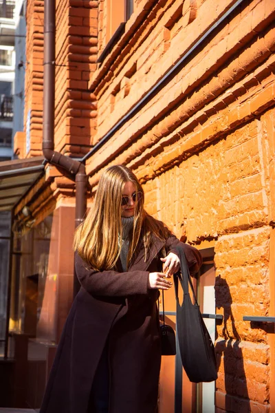Νεαρή γυναίκα με σκούρο παλτό βάζει τα πράγματα σε μαύρη οικολογική τσάντα — Φωτογραφία Αρχείου