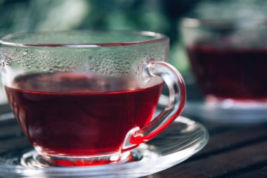 Terastaki ahşap tepside sıcak kırmızı amberçiçeği çayı. Kapat.