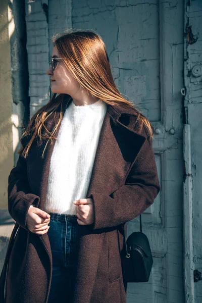 Donna con i capelli lunghi in un cappotto scuro cammina per la strada — Foto Stock