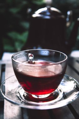 Terastaki ahşap tepside bir bardak sıcak kırmızı amber çayı. Kapat.