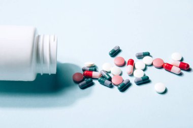 Mavi arka planda beyaz vitamin hapları ve kapsüller. Beslenme takviyeleri. Tamamlayıcı ve tıbbi ürünler