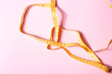 Pembe arka planda izole edilmiş parlak sarı mezura.