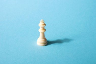Mavi arka planda beyaz satranç kraliçesi. Soyut arkaplan. Satranç taşı. Liderlik kavramı, yalnızlık.