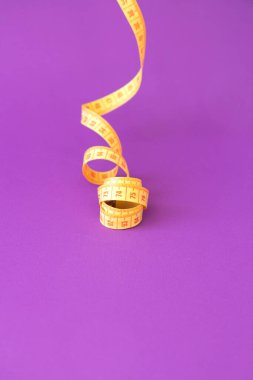 Pembe menekşe arkaplanda izole edilmiş parlak sarı mezura.