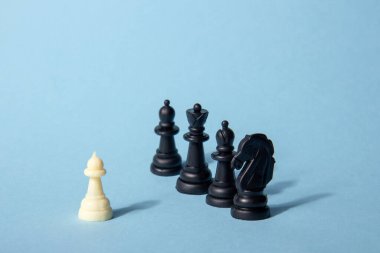 Mavi bir zıt gölgeli arkaplanda siyah satranç taşlarına karşı bir satranç taşı. Soyut arkaplan. Liderlik kavramı