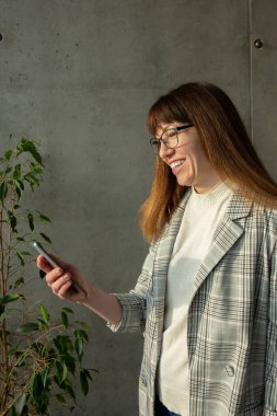 Gözlüklü genç ve güzel bir iş kadını cep telefonuyla konuşuyor.