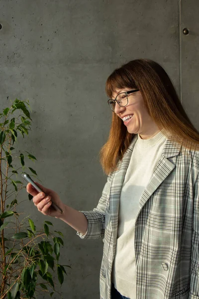 Gözlüklü genç ve güzel bir iş kadını cep telefonuyla konuşuyor.