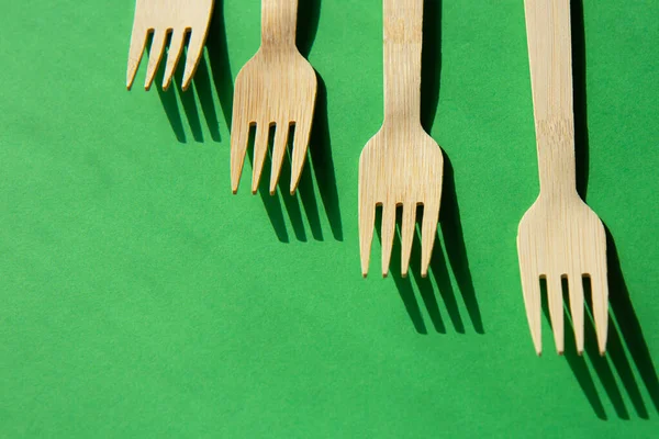 Parlak yeşil zemin üzerinde ahşap eko bambu çatal bıçak takımı