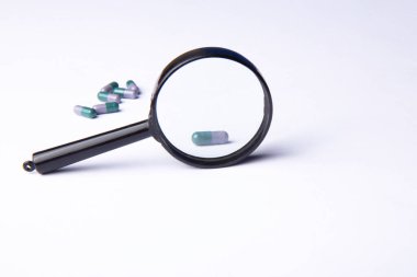 Vitamin hapları ve beyaz arka planda büyüteç. Beslenme takviyeleri ve diyet için haplar