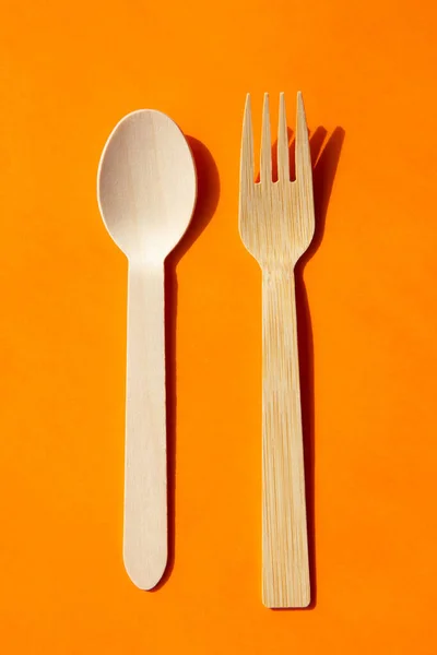 Colher de talheres de bambu de madeira e garfo no fundo laranja brilhante — Fotografia de Stock