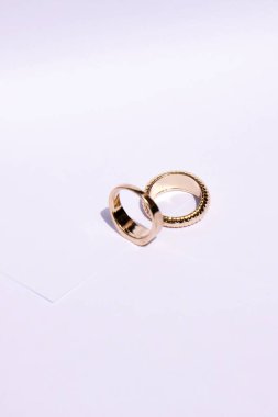 Beyaz arka planda zıt gölgelerle iki altın alyans.