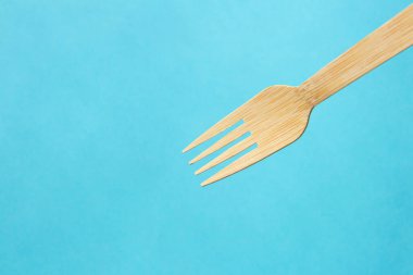 Wooden eco bamboo cutlery fork on bright blue background