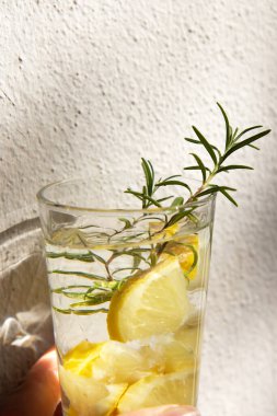 Limonlu soğuk vitamin içeceği ve hafif arka planda biberiye filizi. Yan görünüm