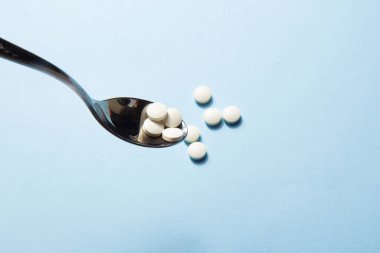 Mavi arka planda demir eksikliği olan beyaz vitamin hapları. Beslenme takviyeleri. Tamamlayıcı ve tıbbi ürünler