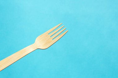 Wooden eco bamboo cutlery fork on bright blue background