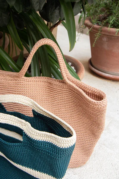 Beige and blue knitted bags handmade outdoors. Sustainable shopping. Waste-free lifestyle. Do-it-yourself jute bag