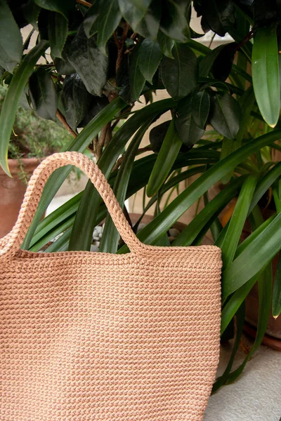 Beige knitted bag handmade outdoors. Sustainable shopping. Waste-free lifestyle. Do-it-yourself jute bag