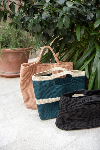 Beige and blue and black knitted bags handmade outdoors. Sustainable shopping. Waste-free lifestyle. Do-it-yourself jute bag