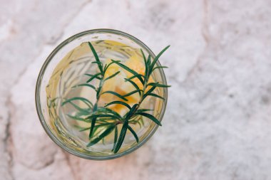 Limonlu soğuk vitamin içeceği ve hafif arka planda biberiye filizi. Kapat.