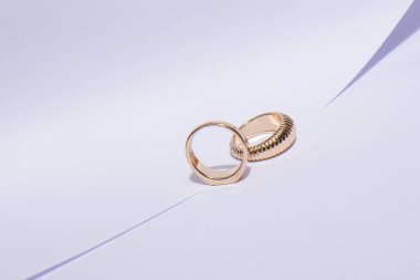 Beyaz arka planda zıt gölgelerle iki altın alyans.