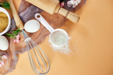 Çiçekli fırın ya da yemek çerçevesi, malzemeler, pastel turuncu arka planda hamur işi için mutfak malzemeleri, bahar pişirme teması. Üst görünüm, alanı kopyala.