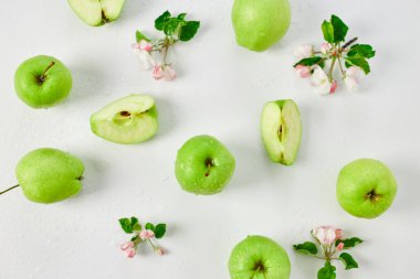 Düz elma çiçekleri ve olgun yeşil elmalar beyaz arka planda, meyveler ve çiçekler, sping konsepti. Üst görünüm