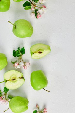 Düz elma çiçekleri ve olgun yeşil elmalar beyaz arka planda, meyveler ve çiçekler, sping konsepti. Üst görünüm