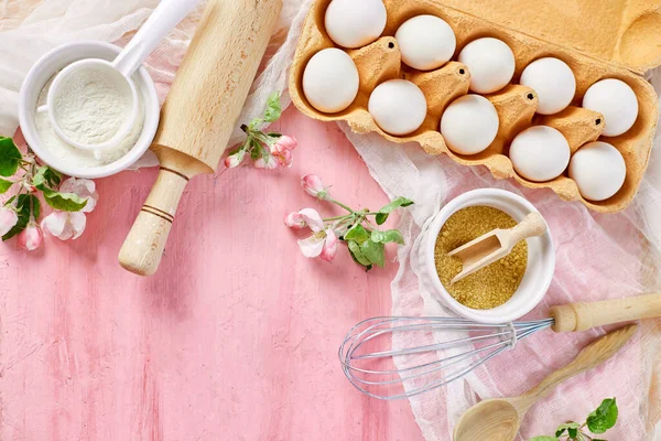 Çiçekli fırın veya yemek iskeleti, malzemeler, pembe arka planda hamur işi için mutfak malzemeleri, bahar pişirme teması. Üst görünüm, alanı kopyala.