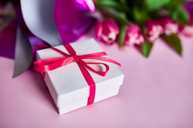 Üst manzara pembe laleler menekşe kağıda sarılıp hediye paketi, şenlikli arka plan, Mutlu Anneler Günü konsepti, Kadınlar Günü, doğum günü, 8 Mart, Sevgililer Günü