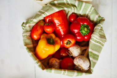 Üst manzara, yeniden kullanılabilir pamuklu poşetlerdeki taze sebzeler, gün ışığında Kitche 'deki masada, tekstil sıfır atık torbalarındaki bakkallar, internette sağlıklı alışveriş, vejetaryen yiyecekler..