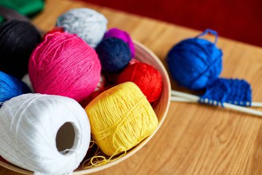 Ahşap masada çok renkli örgü ipliği, sepetteki iplik yumakları örgü iğneleri, kopyalama alanı..