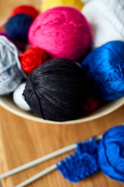 Ahşap masada çok renkli örgü ipliği, sepetteki iplik yumakları örgü iğneleri, kopyalama alanı..