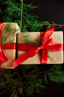 Üst görünüm Noel çevre dostu ambalaj kağıdı ve köknar dalları siyah arka planda Bayram sezonu için hediyeler sunuyor 