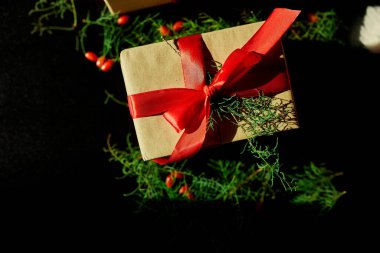 Üst görünüm Noel çevre dostu ambalaj kağıdı ve köknar dalları siyah arka planda Bayram sezonu için hediyeler sunuyor 