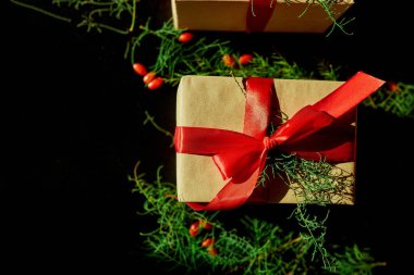Üst görünüm Noel çevre dostu ambalaj kağıdı ve köknar dalları siyah arka planda Bayram sezonu için hediyeler sunuyor 