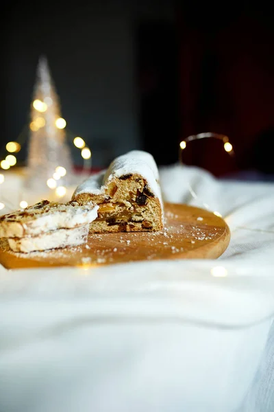 Homemade traditional marzipan Christmas Stollen on white background, with christmas lights and decorations