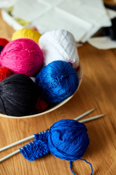 Ahşap masada çok renkli örgü ipliği, sepetteki iplik yumakları örgü iğneleri, kopyalama alanı..
