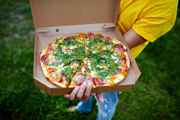 Pizza delivery man,Unrecognizable male, courier delivering pizza in park, open box. Fast Food delivery service concept