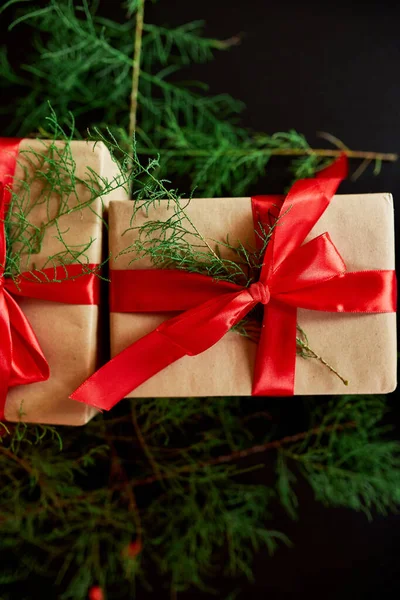 Üst görünüm Noel çevre dostu ambalaj kağıdı ve köknar dalları siyah arka planda Bayram sezonu için hediyeler sunuyor 
