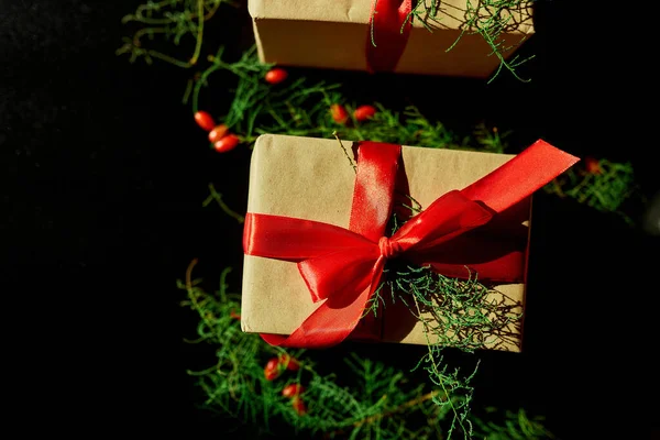 Üst görünüm Noel çevre dostu ambalaj kağıdı ve köknar dalları siyah arka planda Bayram sezonu için hediyeler sunuyor 