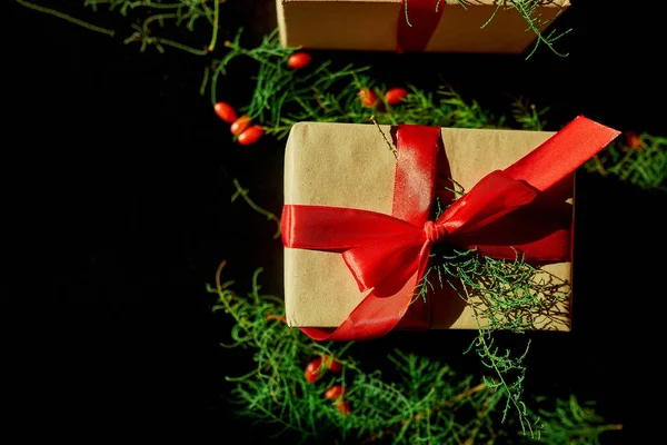 Üst görünüm Noel çevre dostu ambalaj kağıdı ve köknar dalları siyah arka planda Bayram sezonu için hediyeler sunuyor 