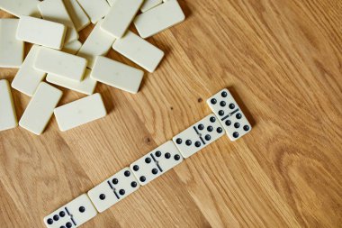 Tahta masa arkaplanındaki beyaz domino oyunlarının en üst görünümü kopya alanı, masa oyunu konsepti