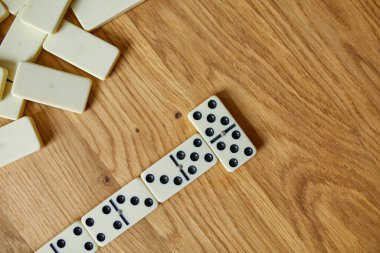 Tahta masa arkaplanındaki beyaz domino oyunlarının en üst görünümü kopya alanı, masa oyunu konsepti