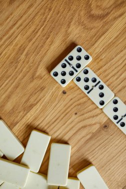 Tahta masa arkaplanındaki beyaz domino oyunlarının en üst görünümü kopya alanı, masa oyunu konsepti