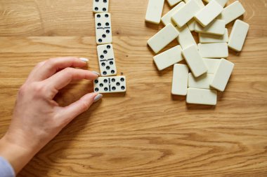 Kadın el oyunlarının üst görünümü tahta masa arkaplanındaki beyaz domino oyunları kopya alanı, masa oyunu konsepti