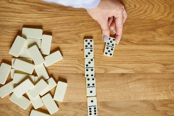 Kadın el oyunlarının üst görünümü tahta masa arkaplanındaki beyaz domino oyunları kopya alanı, masa oyunu konsepti