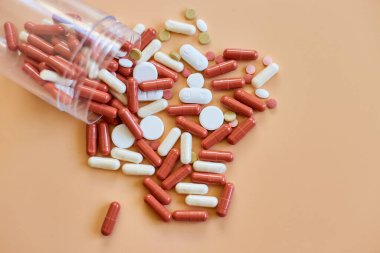 Flat turuncu arka planda şişe ile farklı renkli tıbbi haplar, vitamin eksikliği, avitaminoz konsepti, çeşitli ilaç hapları, diyet takviyesi sağlık ürünleri.