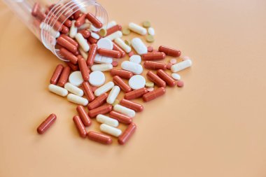 Flat turuncu arka planda şişe ile farklı renkli tıbbi haplar, vitamin eksikliği, avitaminoz konsepti, çeşitli ilaç hapları, diyet takviyesi sağlık ürünleri.