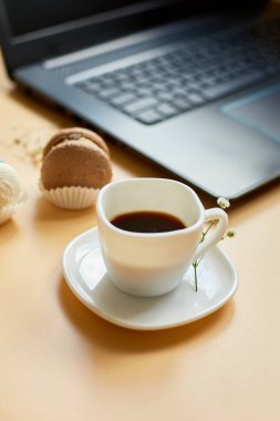 Düz uzanış, üst düzey ofis masası, dizüstü bilgisayarlı çalışma alanı, kahve fincanı ve çiçekli badem kurabiyesi, turuncu arka planda, evden çalışma, uzak çalışma